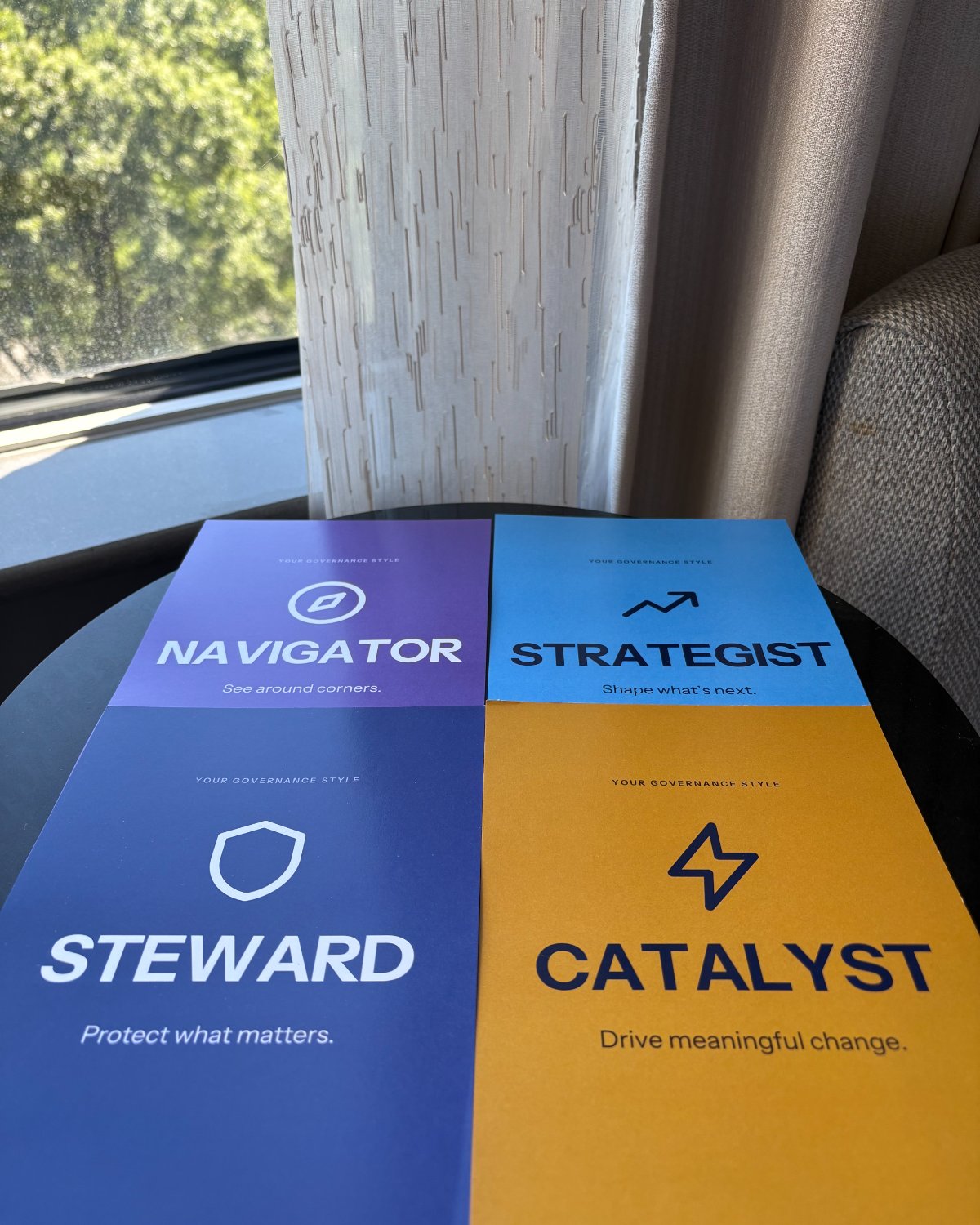 Four printed cards on a table by a window, labelled Your Governance Style: Navigator, “See around corners”; Strategist, “Shape what’s next”; Steward, “Protect what matters”; and Catalyst, “Drive meaningful change.”